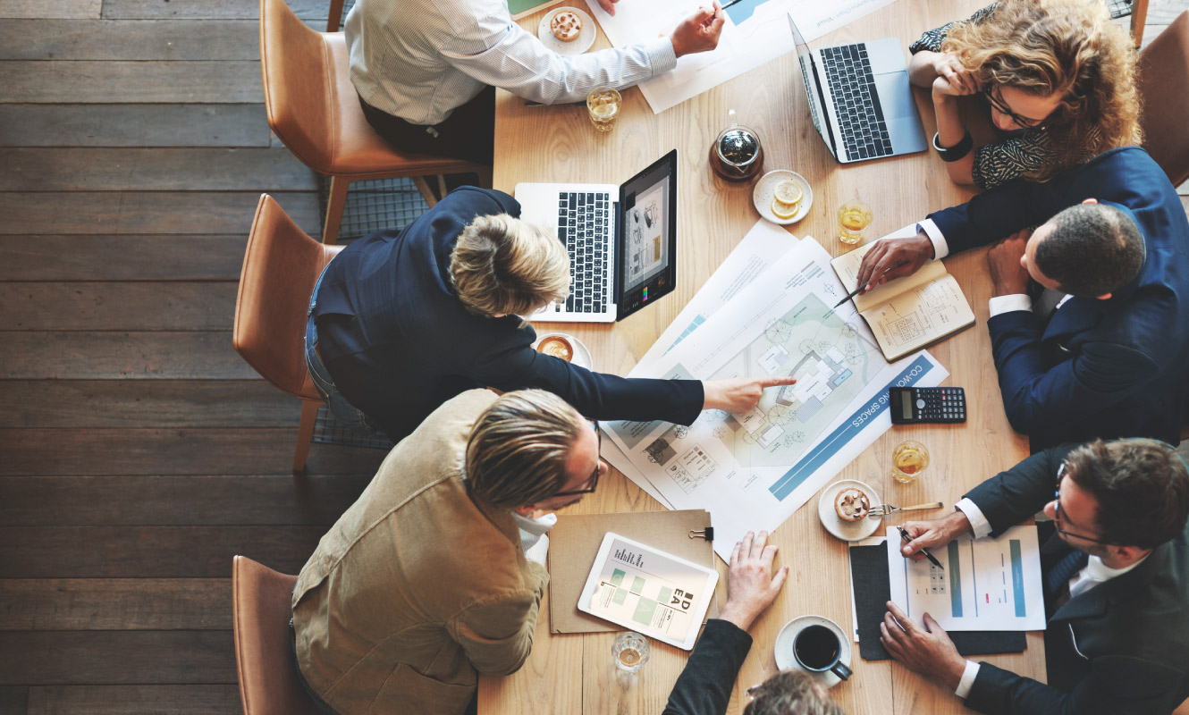 Business coworkers sit around a conference table discussing their plan