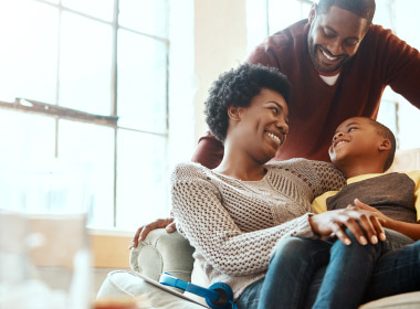 Joyful family of three look at one another while mom and son sit on the couch