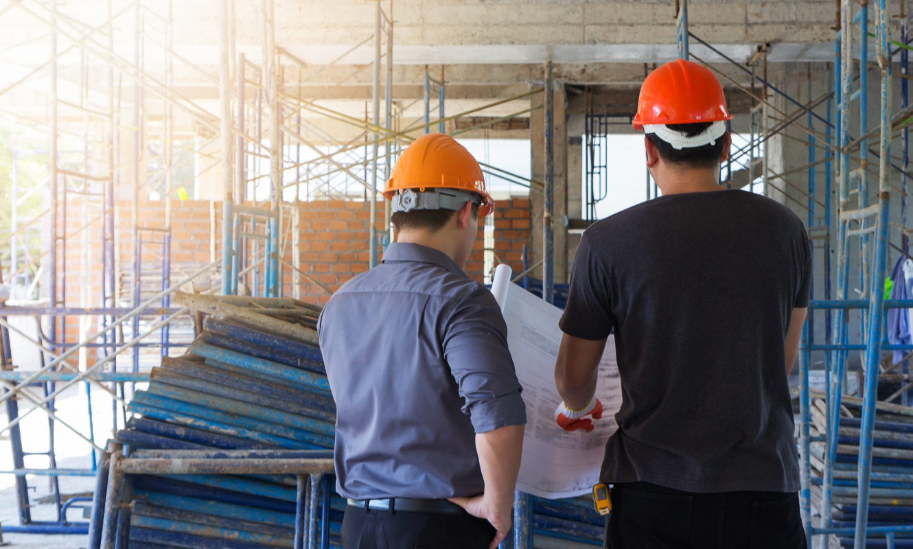 Two construction men review blueprints in a work zone