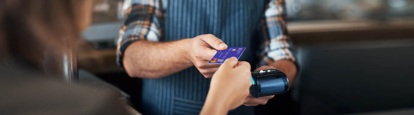 Woman handing over debit card tom make a purchase with a merchant