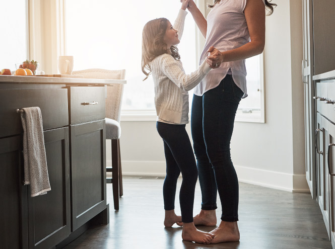 Mother and daughter dance joyfully in the kitchen