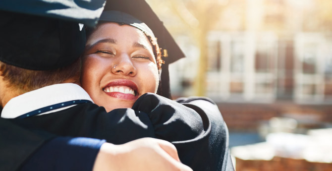 Two proud graduates embrace one another after their accomplishments