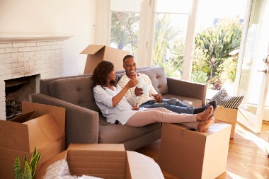 Couple moving into new home drinking coffee on the couch
