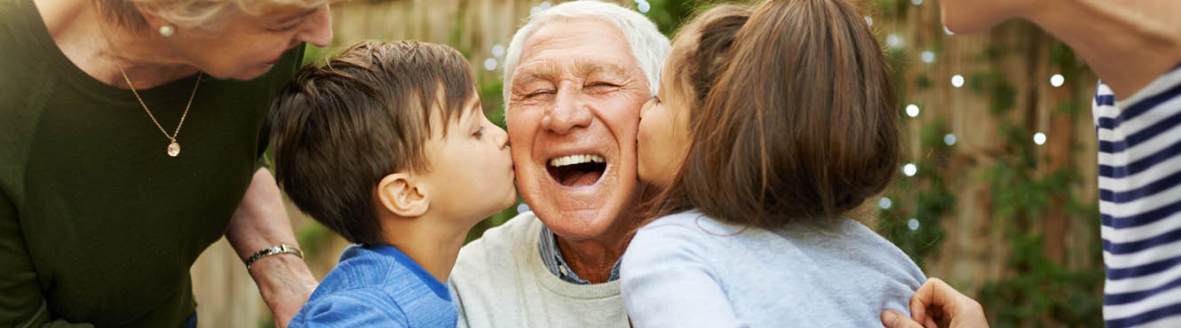 Family celebrating grandpa's birthday with birthday kisses.