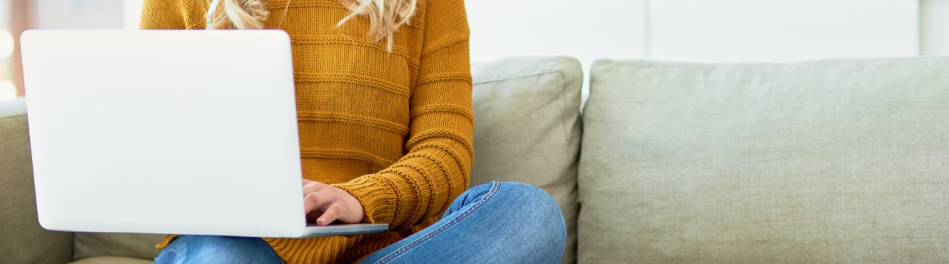 Lady sitting on couch on laptop.