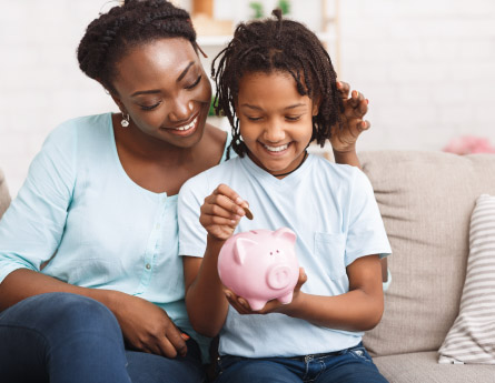 Mother and daughter saving money in a piggy bank.