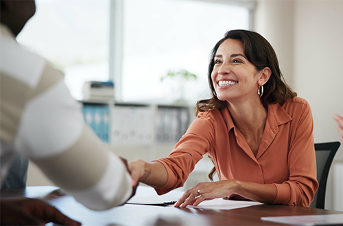 Woman shaking hands and smiling with a personal banker.