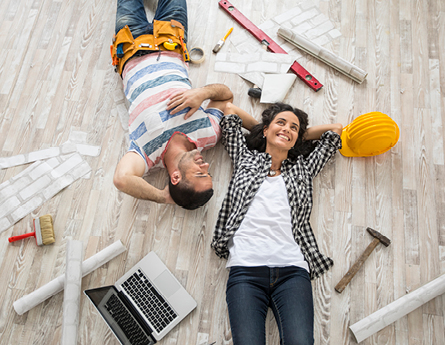 man and woman laying on ground surrounded by construction items.