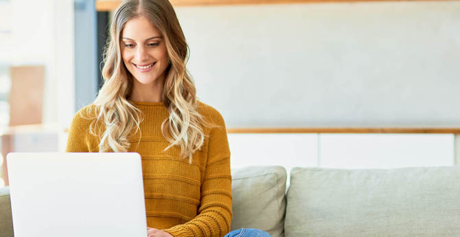 Woman sitting on couch using laptop.