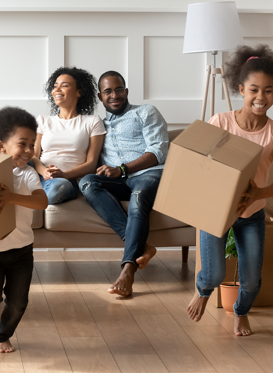 Married couple with young son and daughter smiling carrying boxes