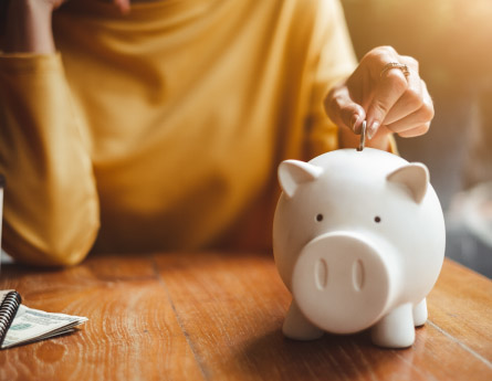 Woman putting money in a piggy bank - Compound Interest - Civista Bank