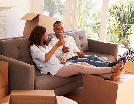 Couple drinking coffee in new home while sitting on couch.