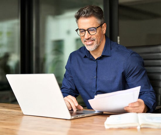 Business_Man-on-computer-with-papers