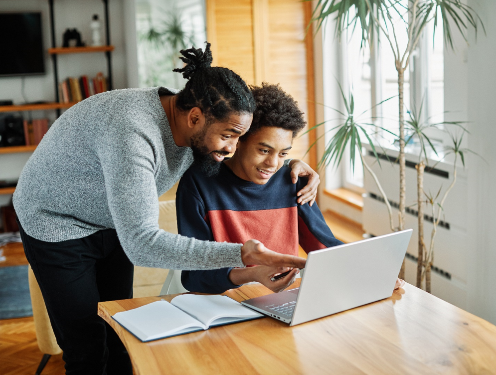 Father and teen son on laptop together