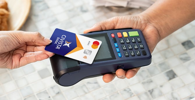 Someone using their debit card to tap to pay