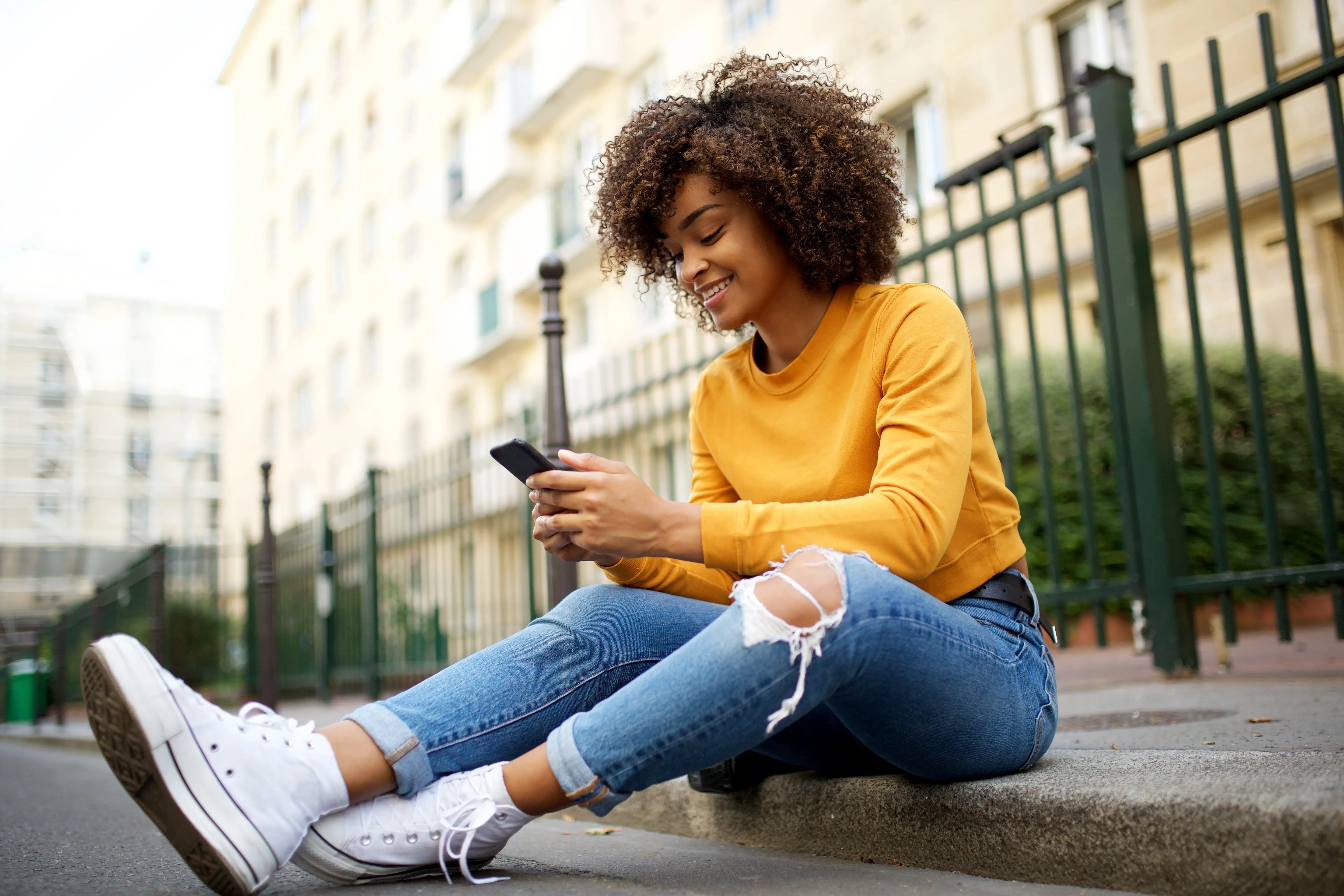 African American woman sitting outside with phone