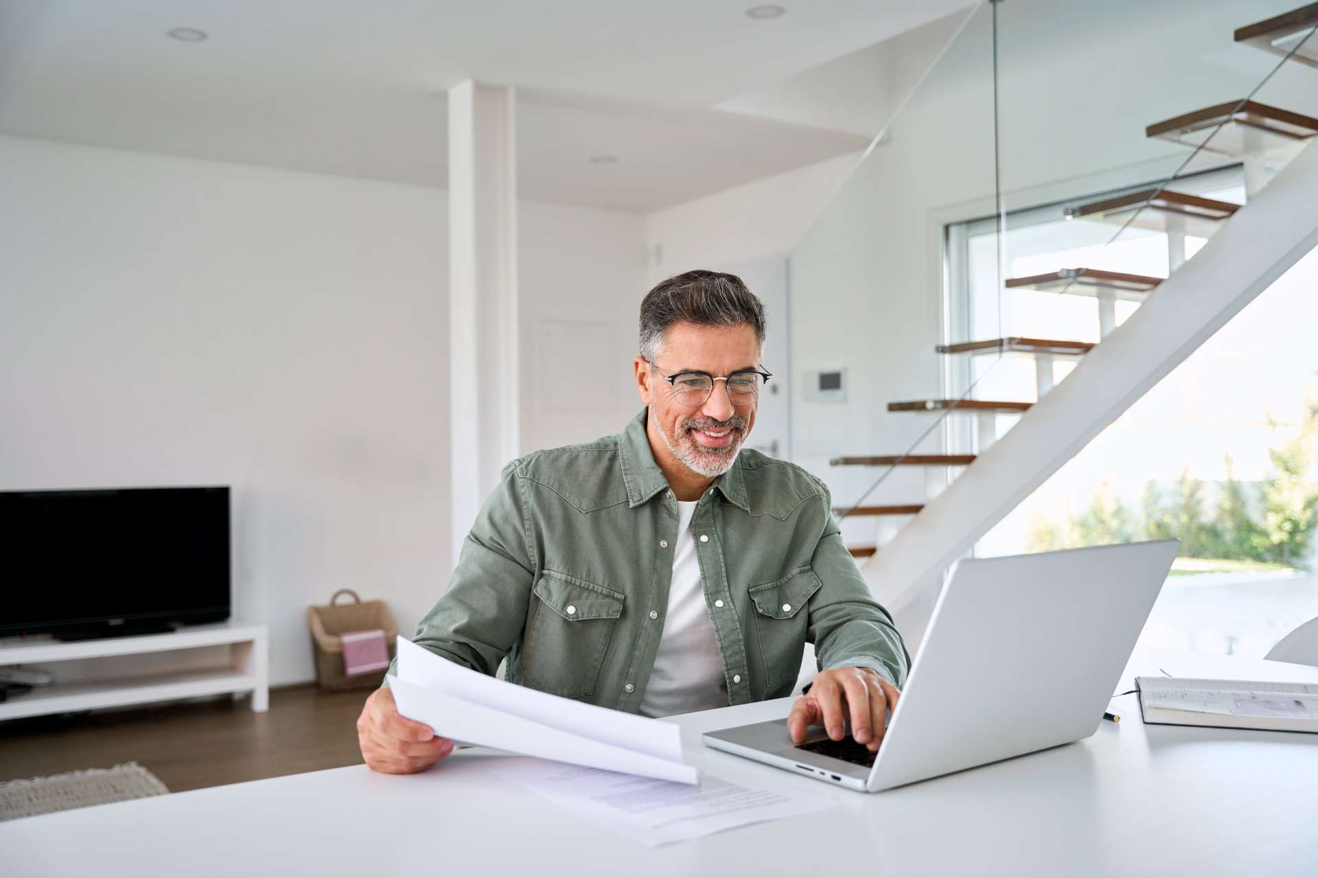 Happy-mature-man-looking-at-laptop-holding-paper-bill-working-at-home. (1)