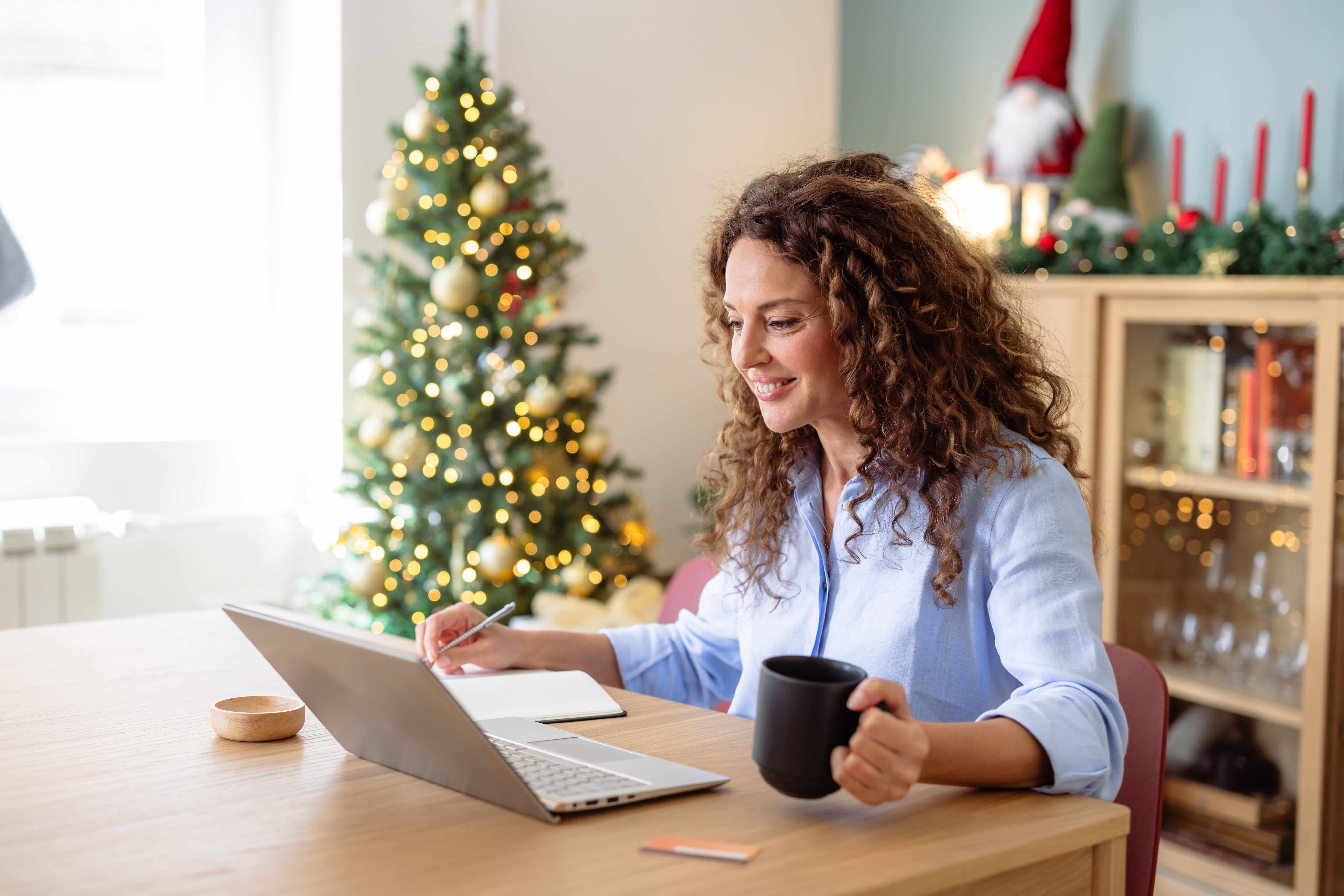 Mid adult woman working on laptop at home during Christmas (1) (1)
