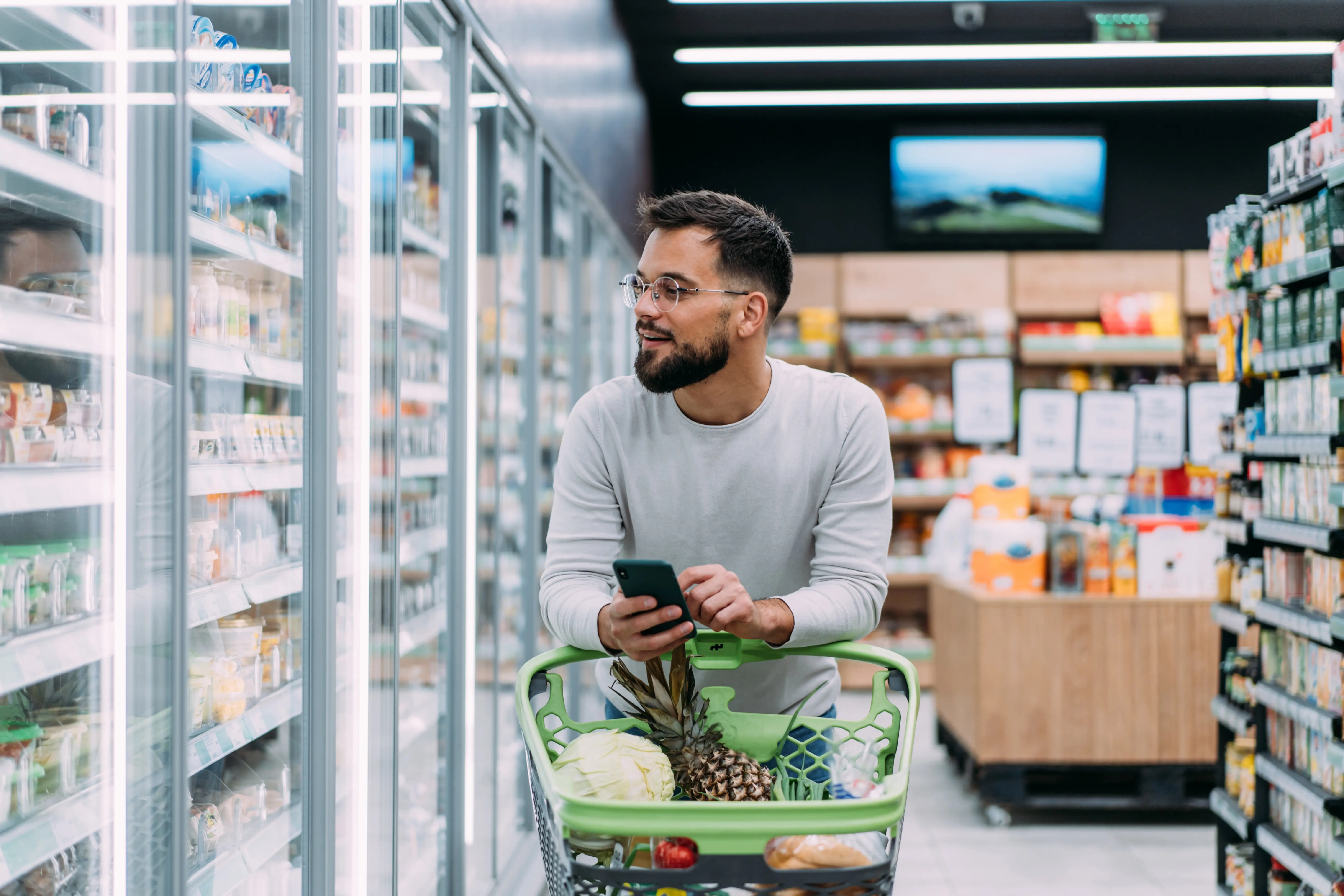 Shot of a young man using a smartphone while shopping in a grocery store