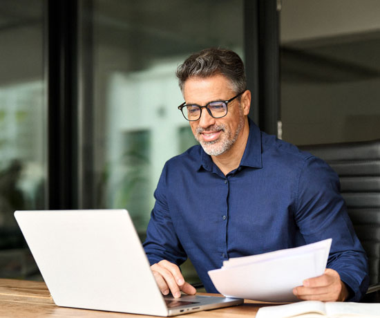 Business_Man-on-computer-with-papers