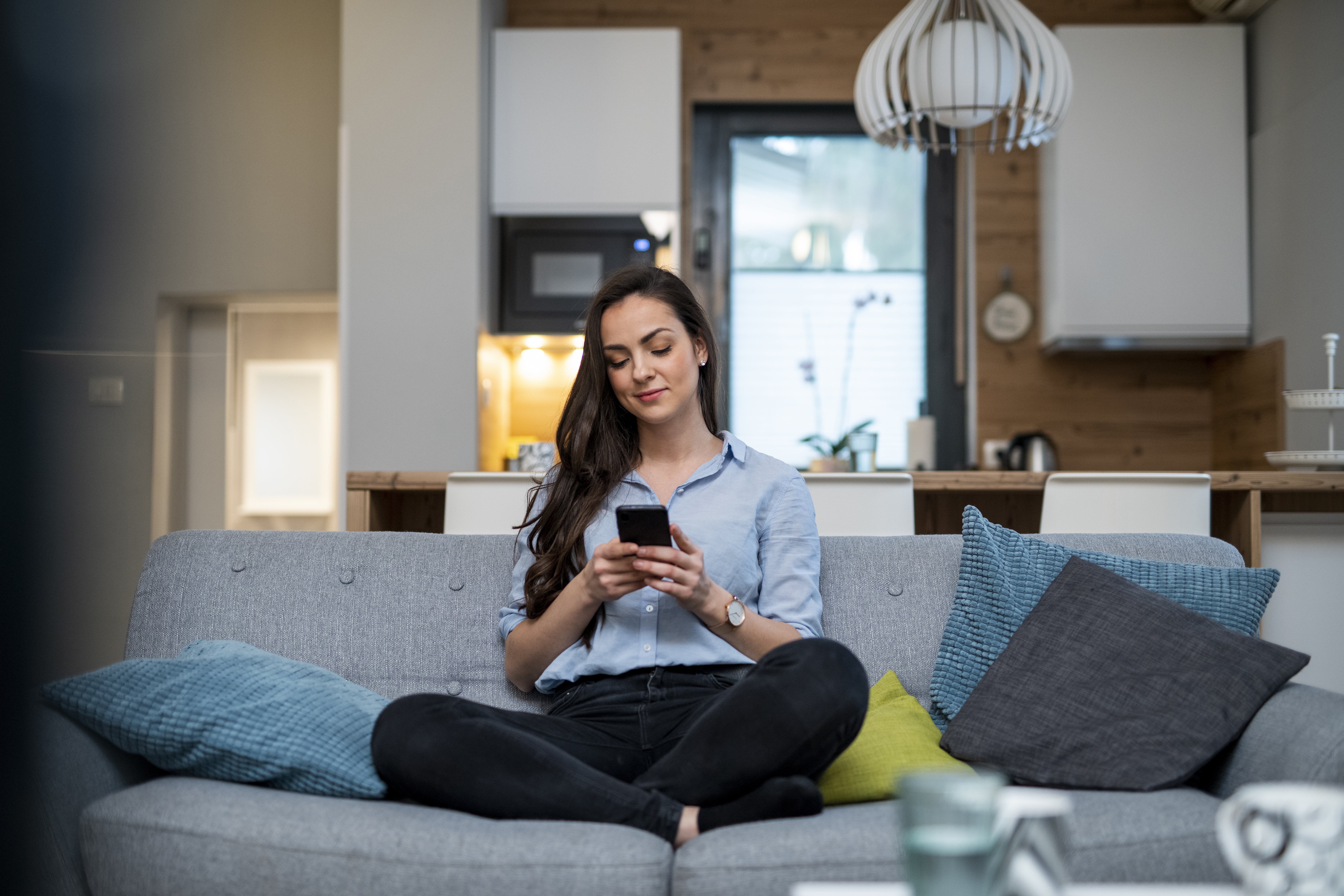 Young woman sitting on the couch and using smart phone