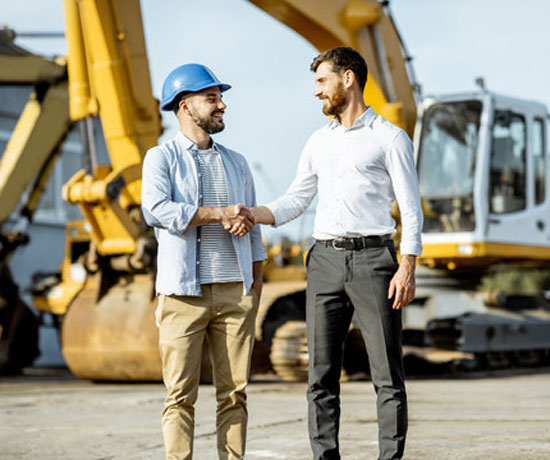 Builder shaking hands with a professional with heavy equipment