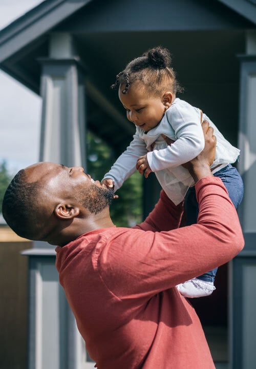 African American dad with baby in front of house