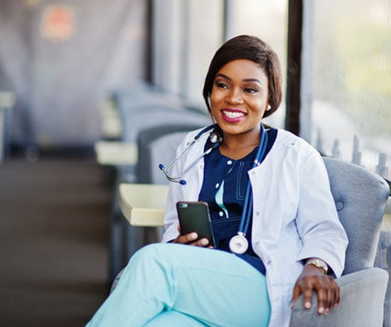 African-american-doctor-female-with-stethoscope-looked-at-phone-and-sitting-on-clinic
